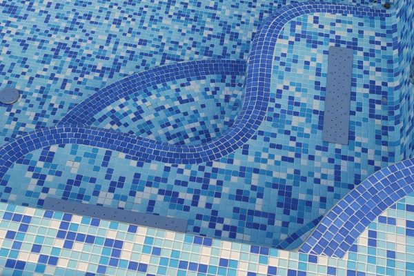 Detalj plavih mozaik pločica s dekorativnim valovitim uzorkom u bazenu